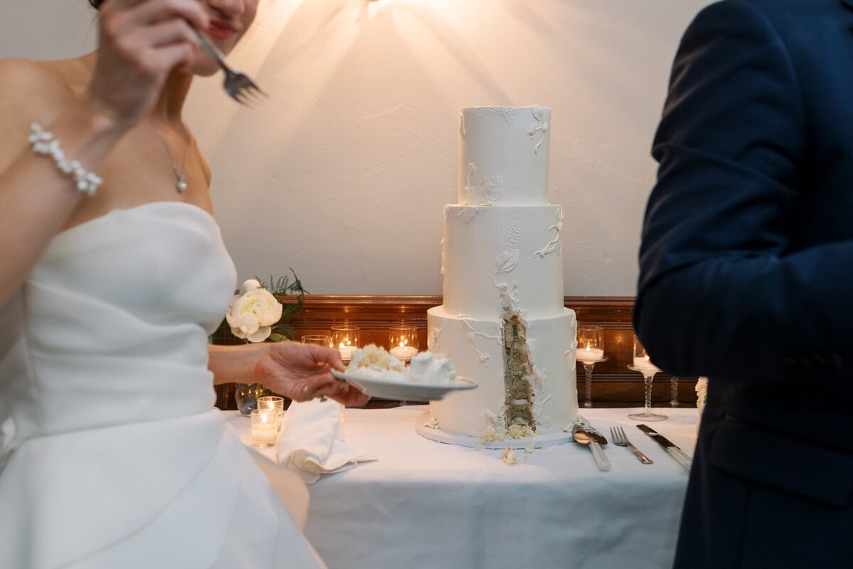 Photo of the cake after being cut with the bride eating it in the foreground