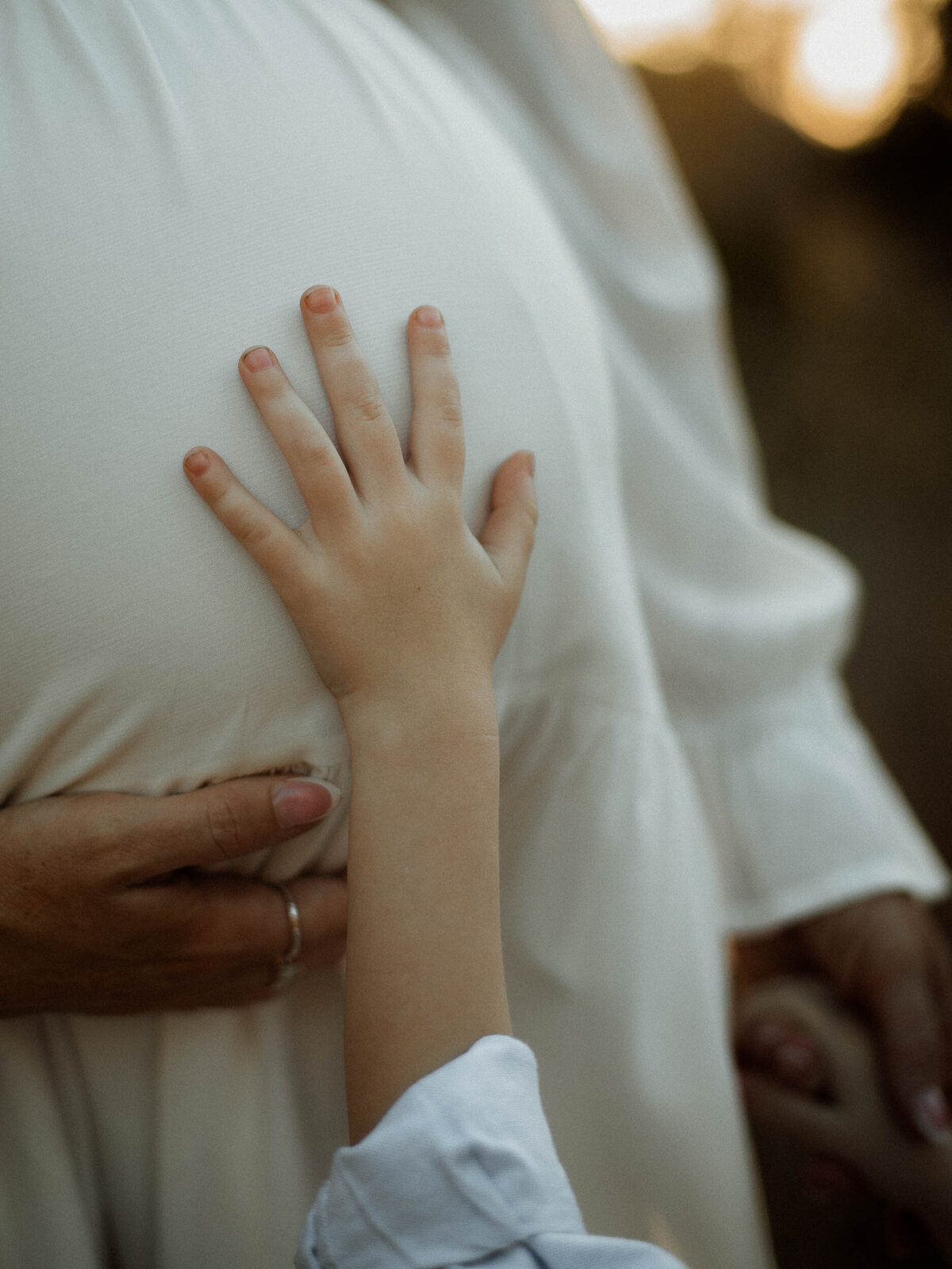 A child's hand resting on mom's baby bump during a maternity session in Murrieta.