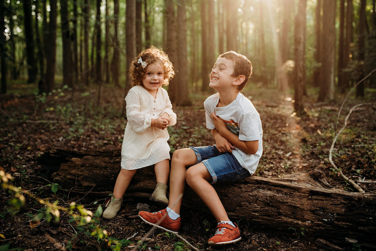 Boy and Girl Laughing on a log in a  forest near washington DC