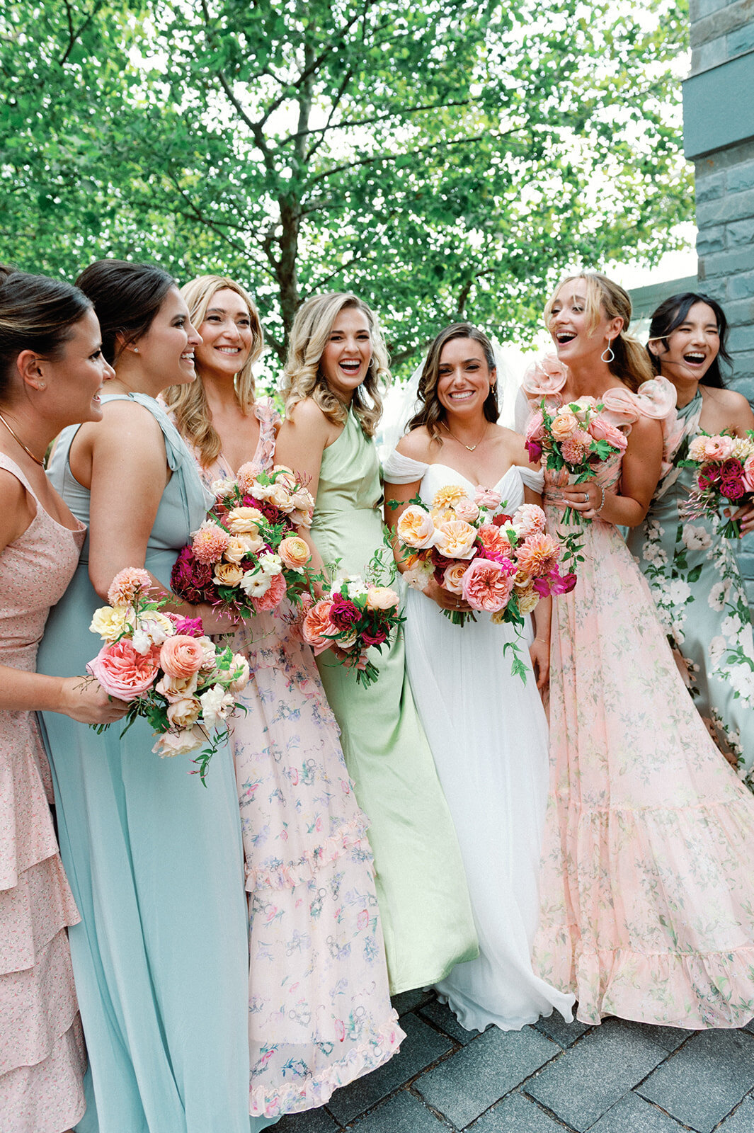 Bridetribe holding their bouquets wearing colorful gowns having fun