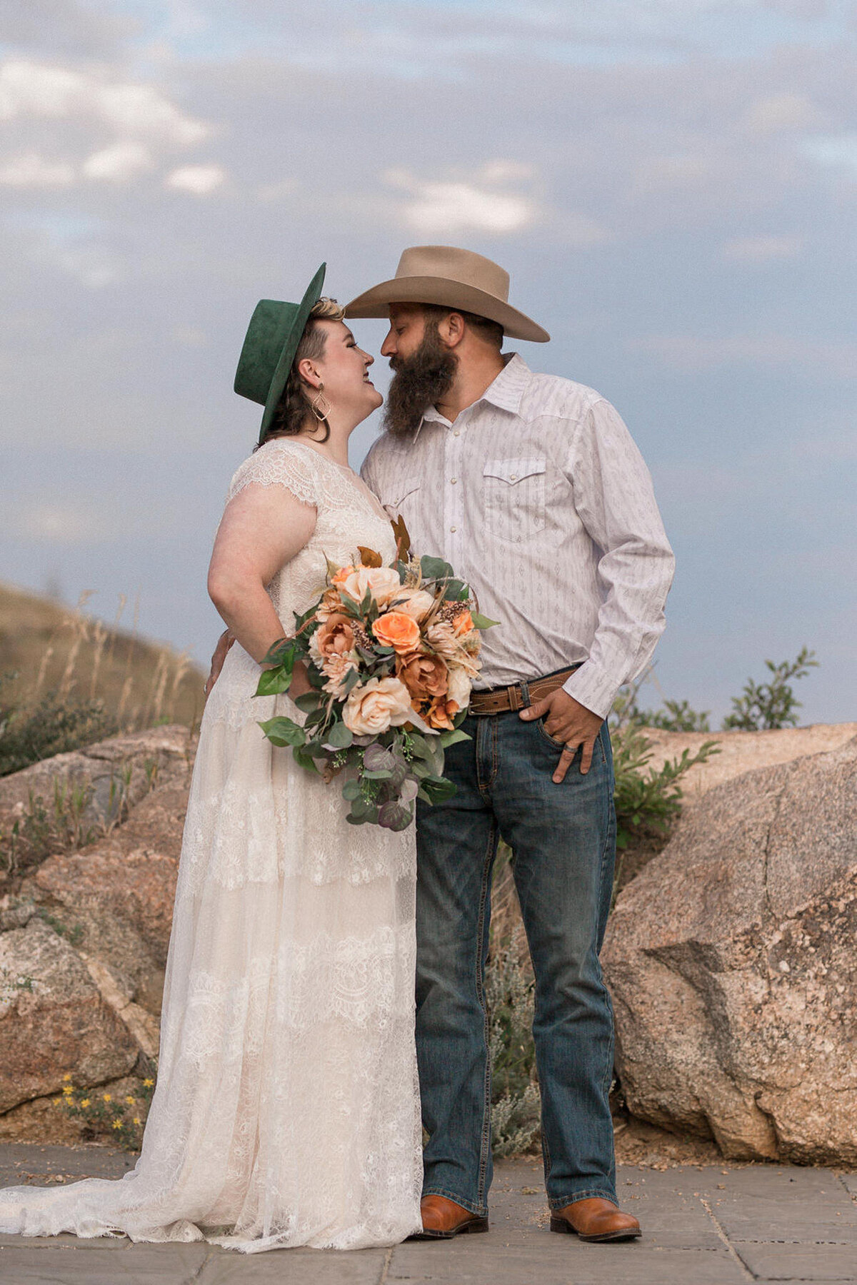 The newly married couple, surrounded by rocky terrain,  gaze into each others eyes while smiling brightly