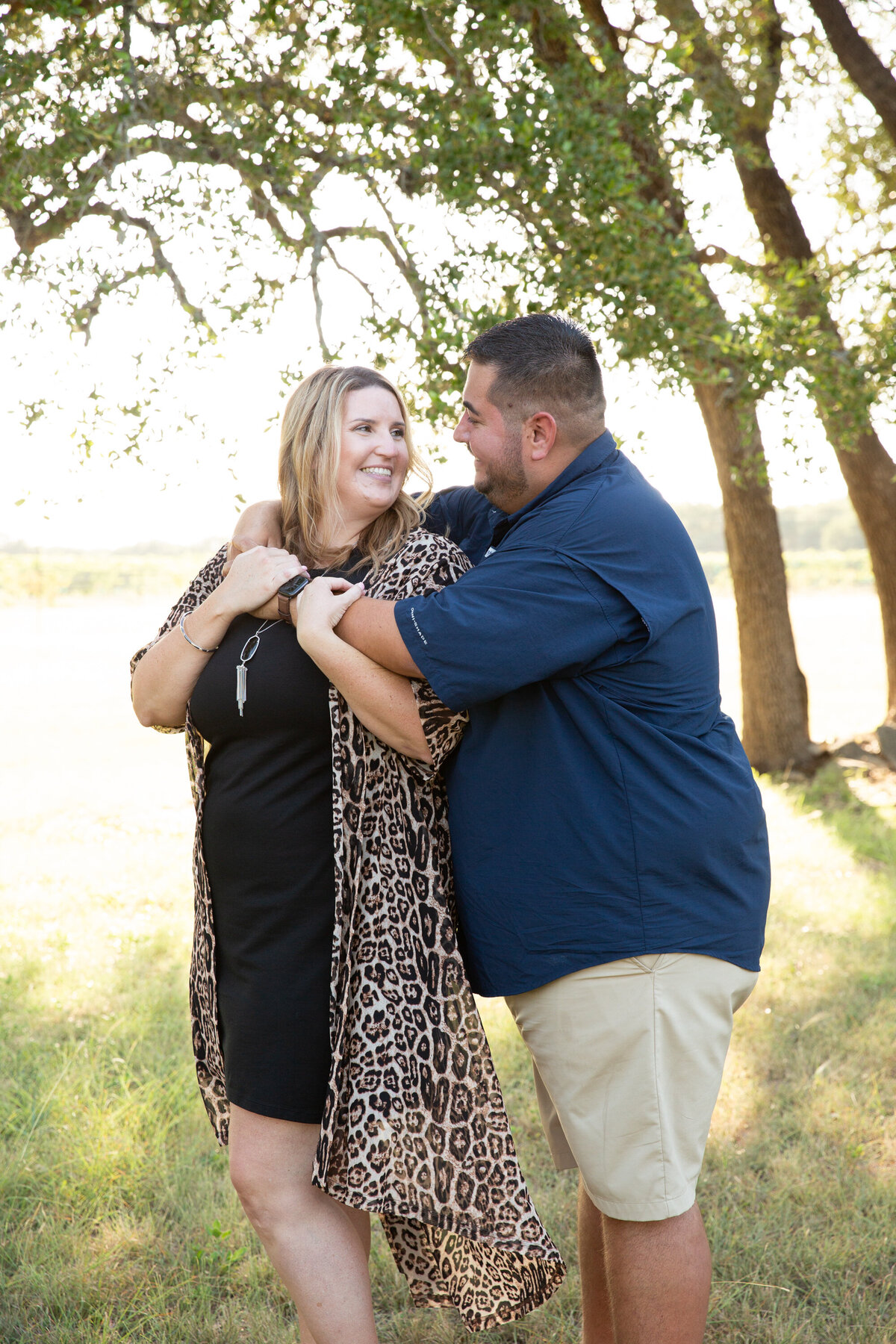 A couple hugging under a tree during their engagement session captured by an Austin wedding photographer.