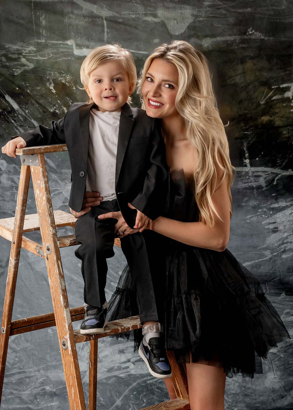 Mom smiles while holding her son on a ladder for their Pella Family Pictures