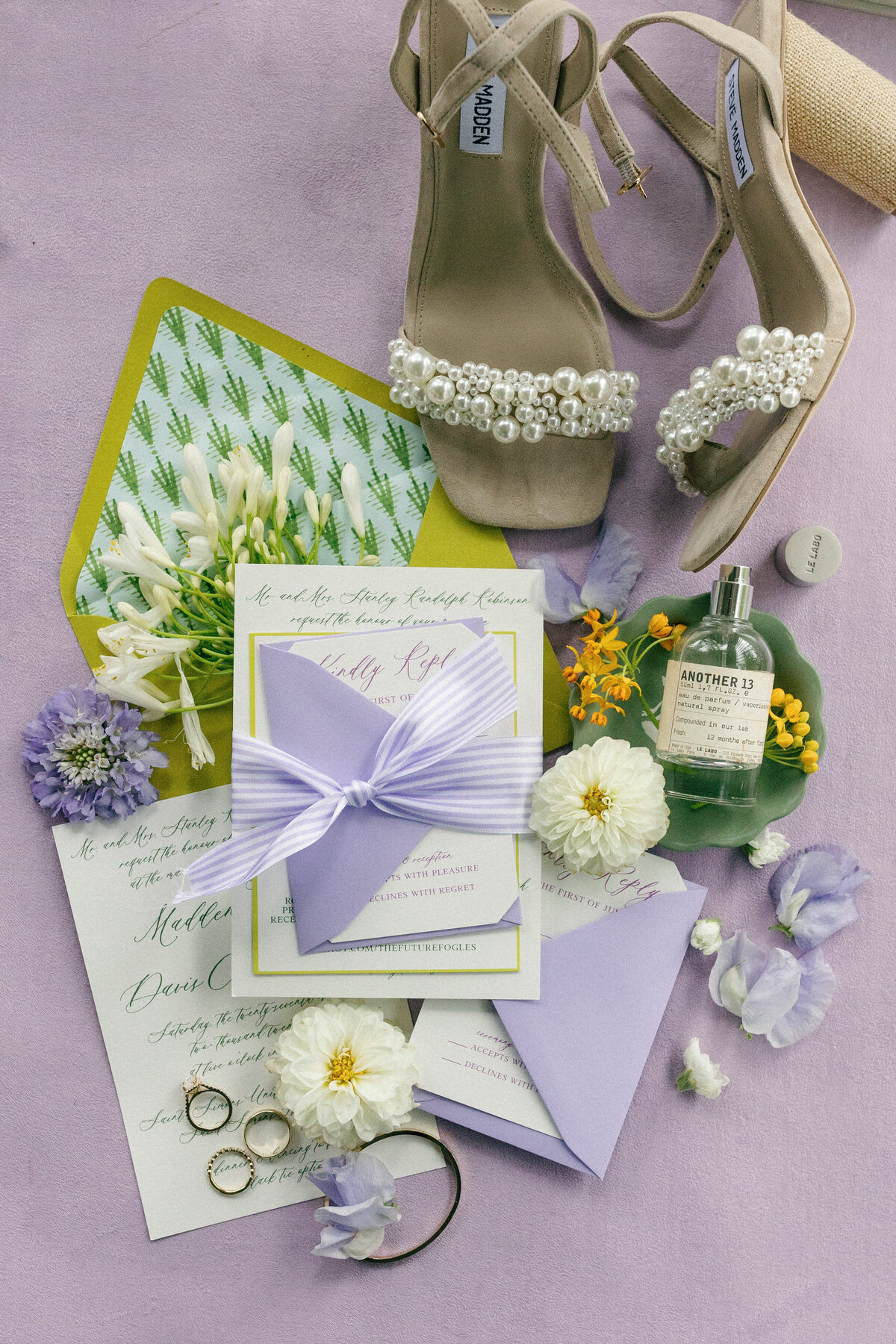 a flat lay for a wedding with a purple, green, and yellow color scheme