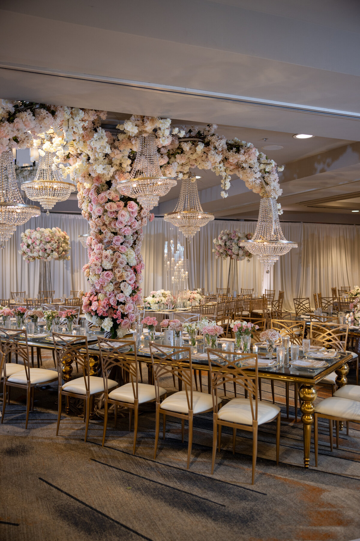 A reception hall with a large flower covered pillar in the middle