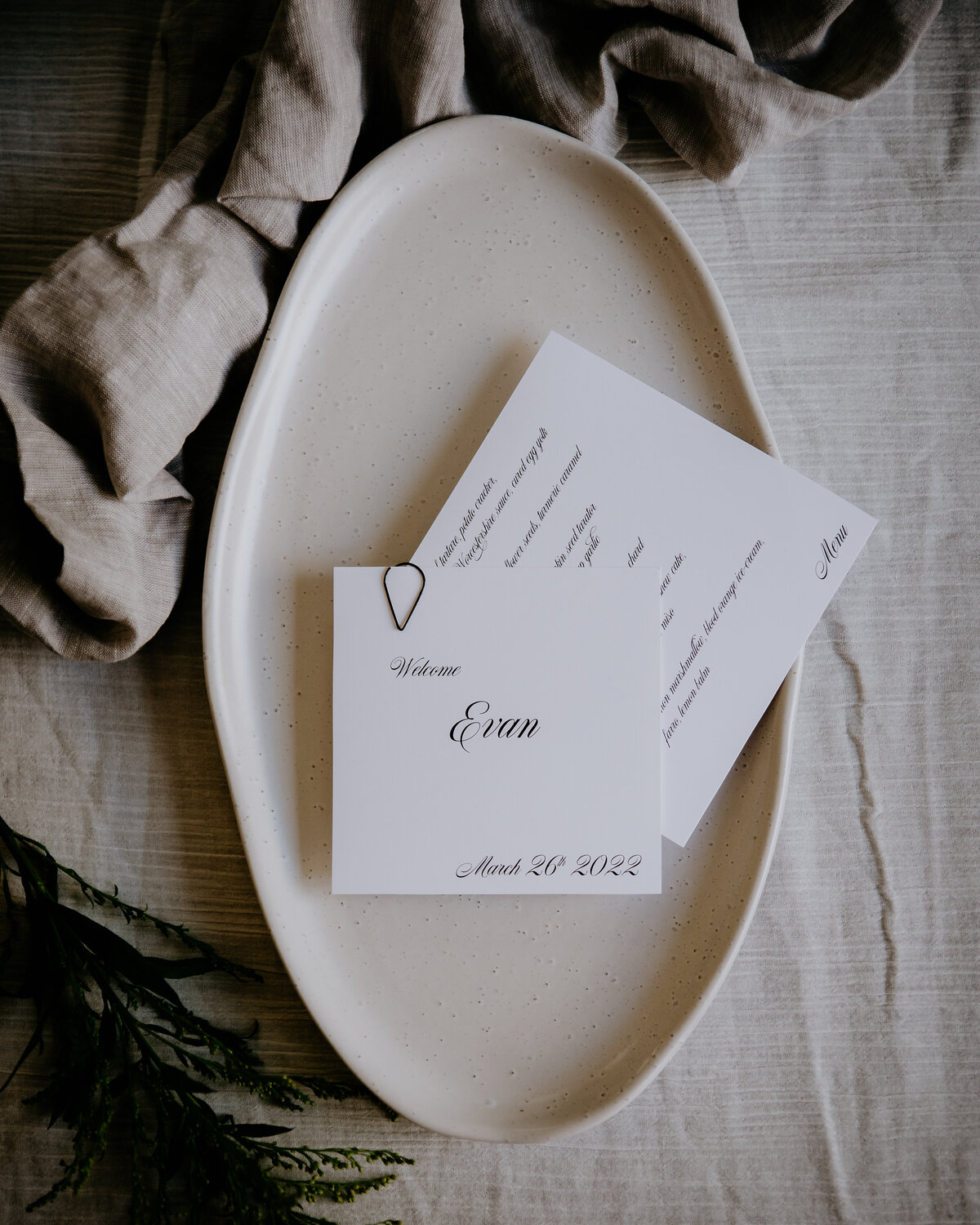 Layered white wedding menu and place card featuring couples wedding date and black teardrop clasp