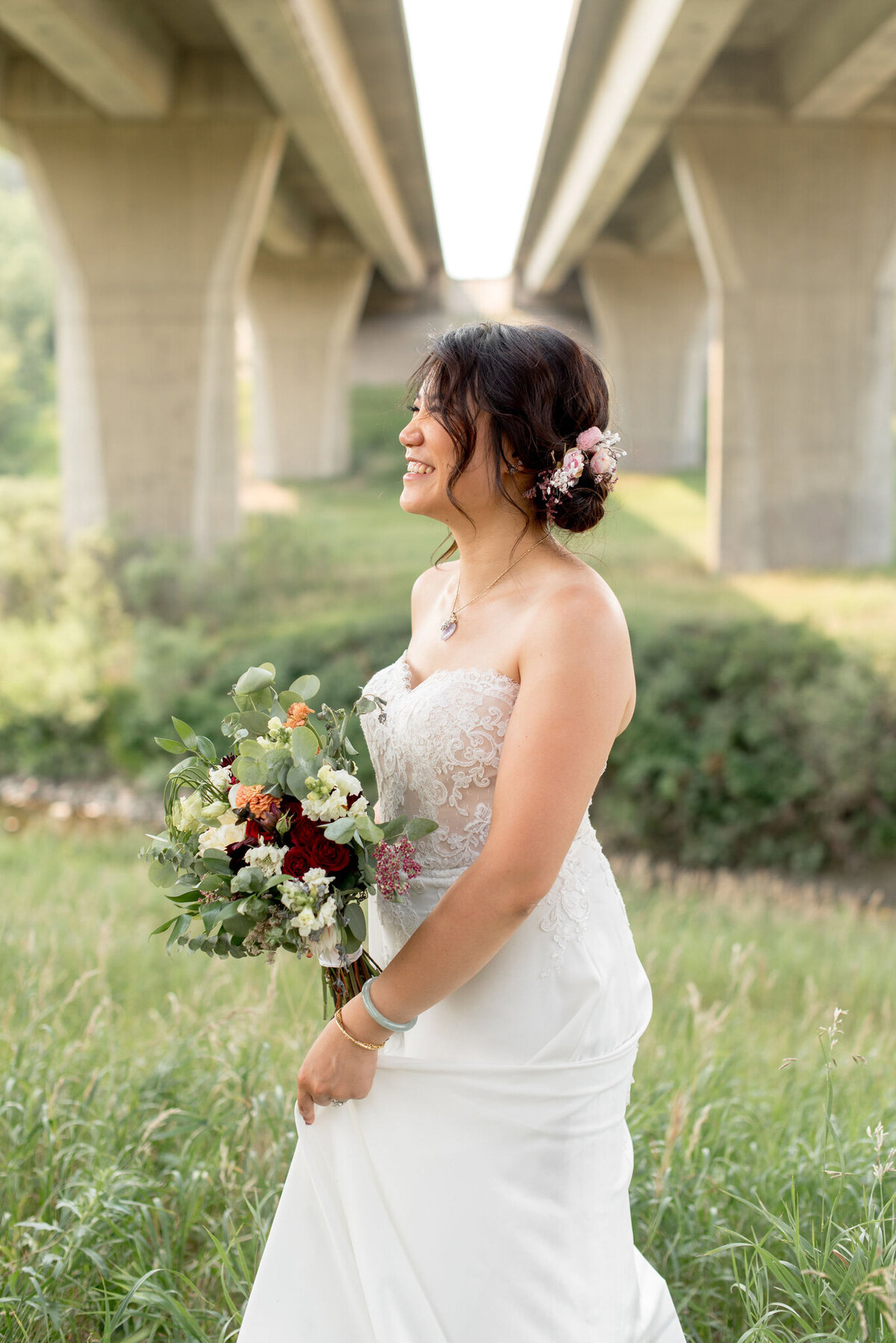 Stunning bride in a gorgeous standing under a bridge wearing a gorgeous, classic A-line wedding gown, with a lace bodice, captured by Janelle Dudzic Photography, colourful and candid wedding photographer in Edmonton, Alberta. Featured on the Bronte Bride Vendor Guide.