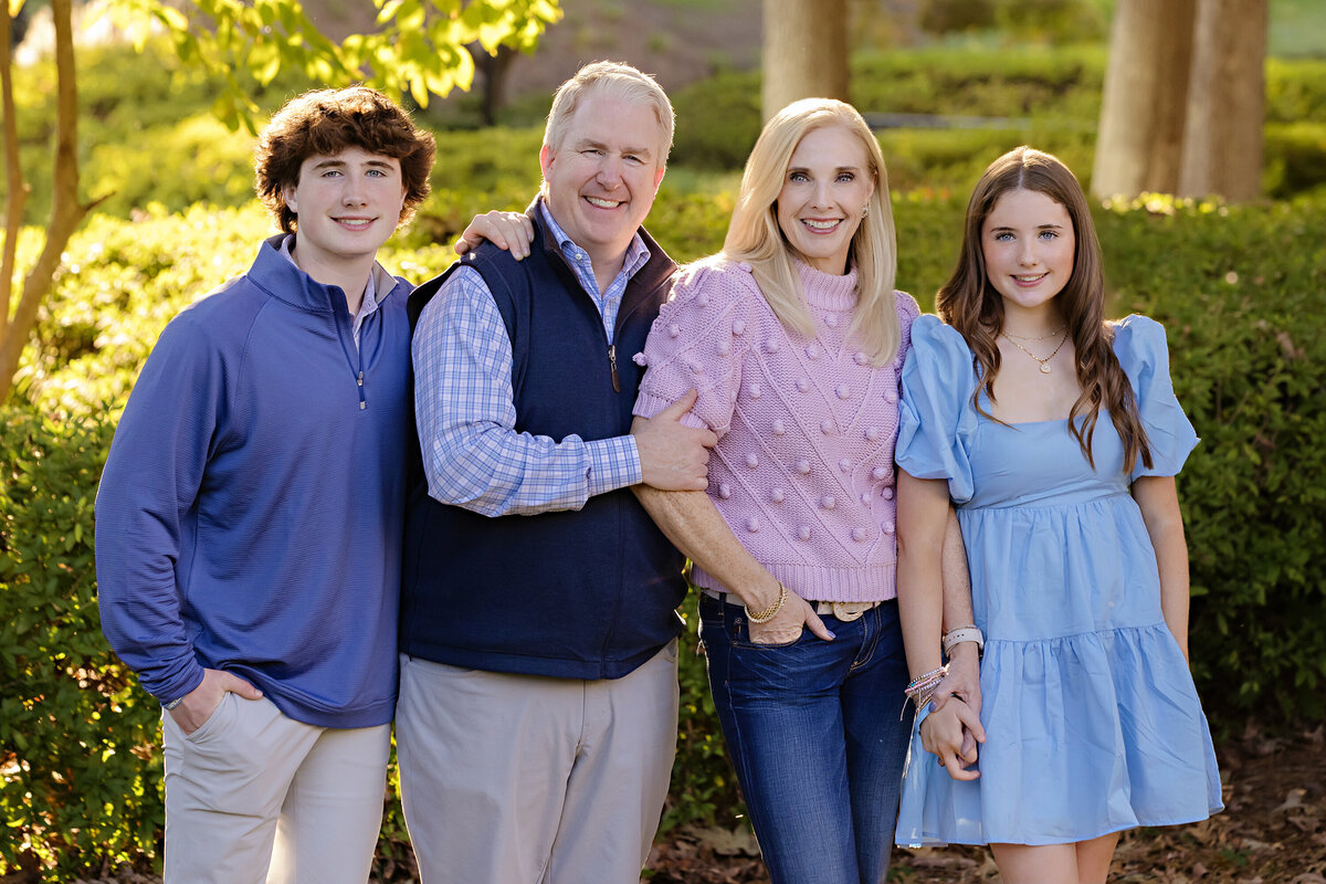 Family of four standing among vibrant greenery in Ballantyne Charlotte NC, relaxed and polished in casual fall layers.