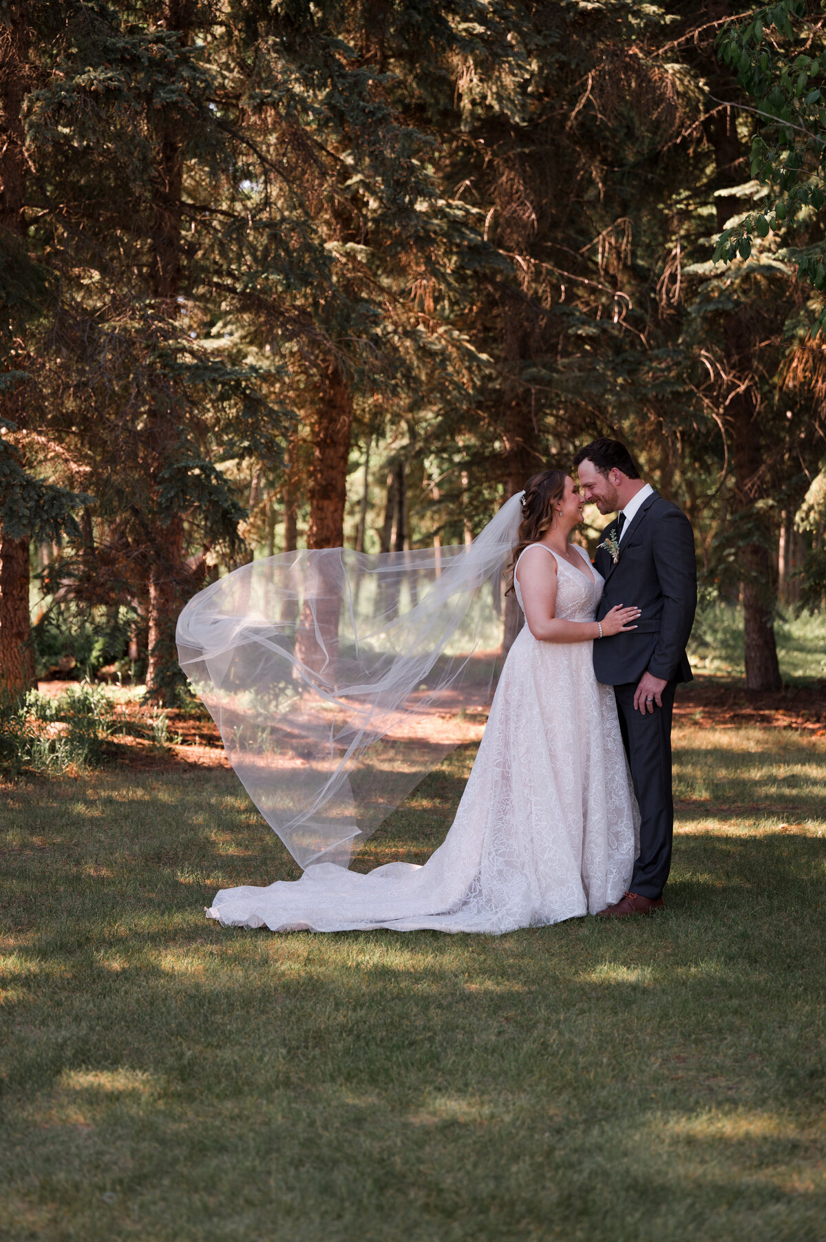 bride and groom facing each other, brides veil is blowing in the wind