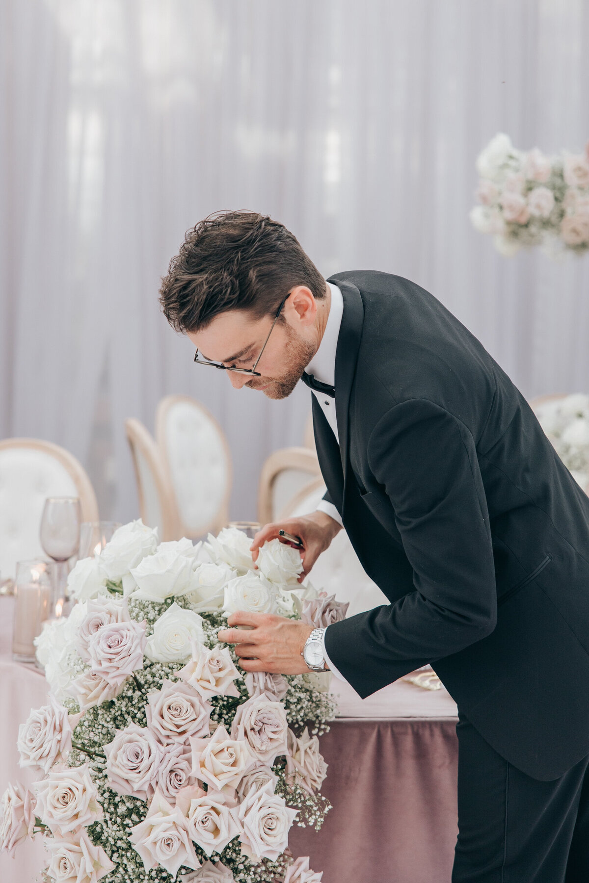 Wedding florist arranging white roses for glamorous wedding dinner