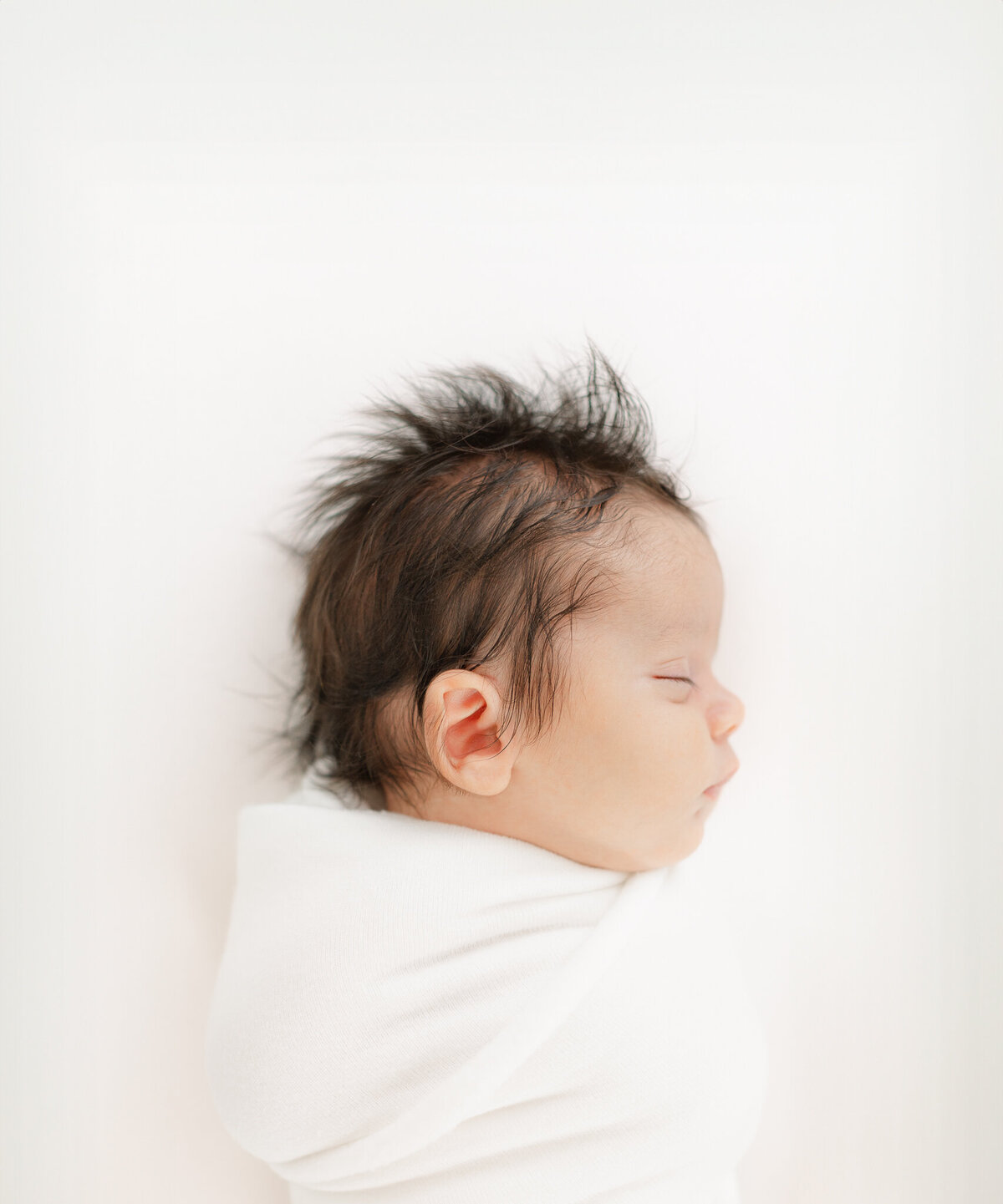 side profile image of newborn baby with dark hair