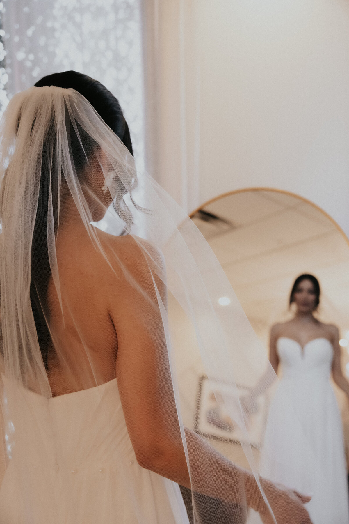 Bride in wedding gown looking in mirror