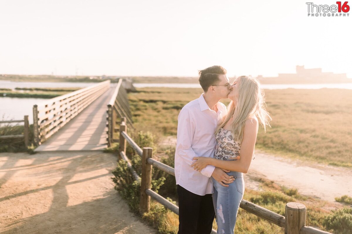 Engaged couple share a kiss during engagement session at the Bolsa Chica Ecological Reserve