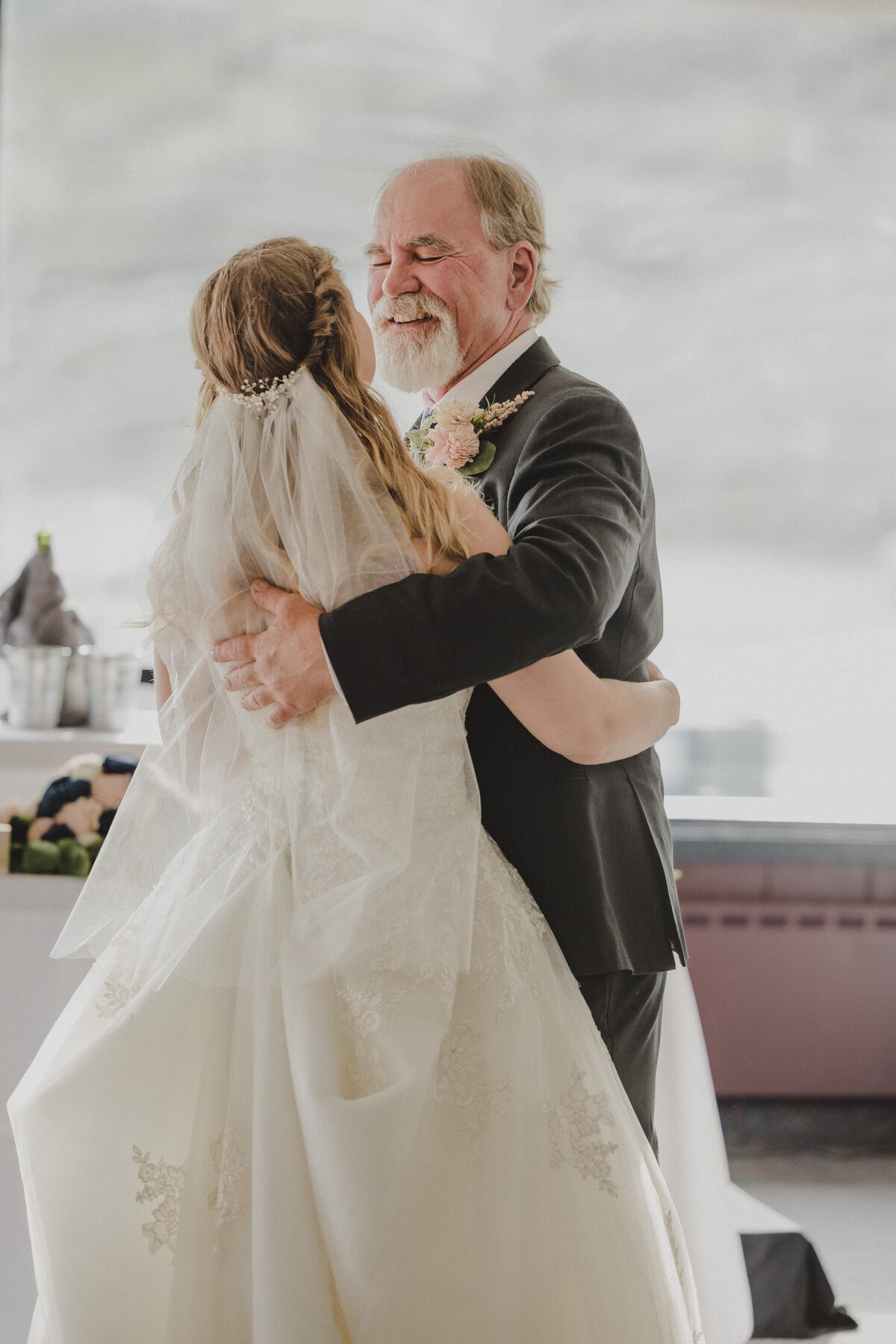 A father and bride laugh during their dance together