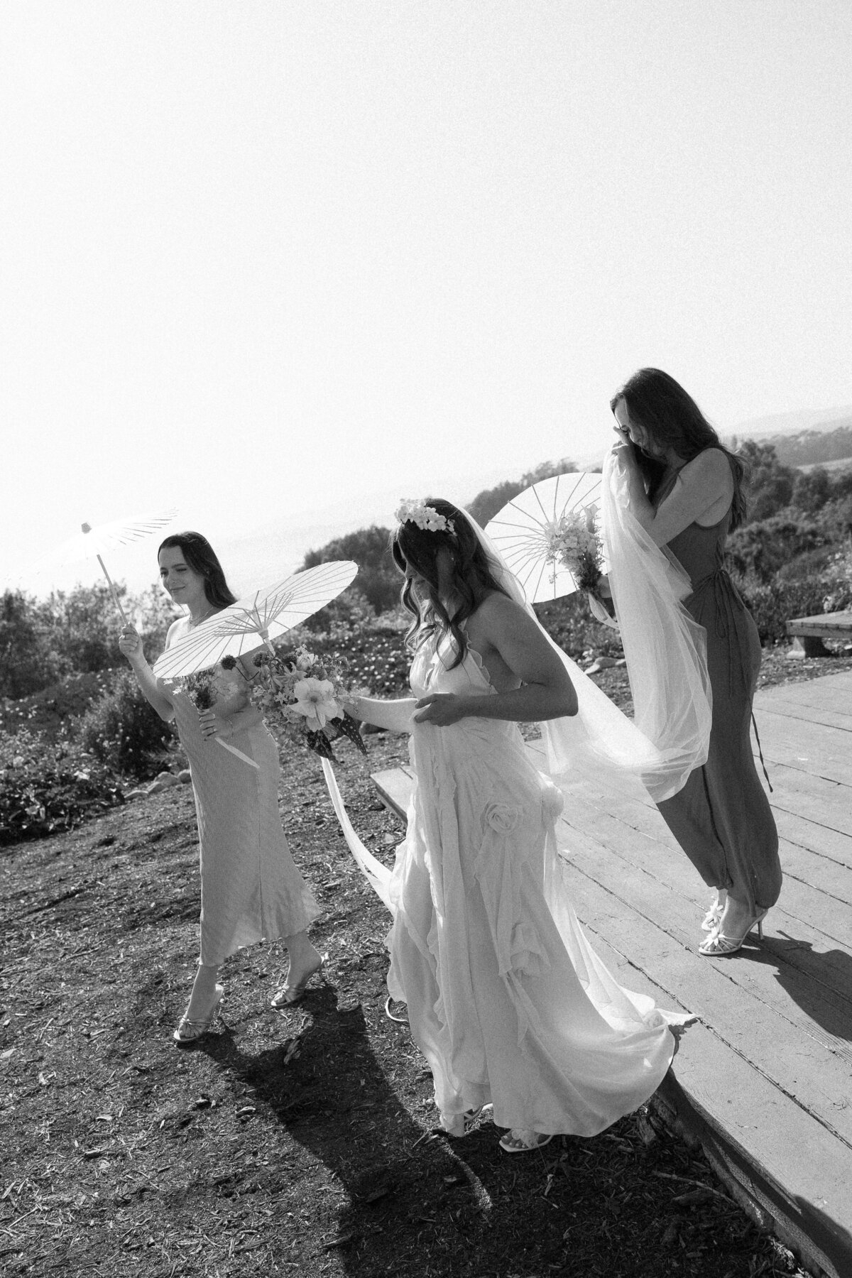 Bridesmaids assisting the bride with her flowing veil as they walk together at a scenic La Jolla wedding in Southern California.