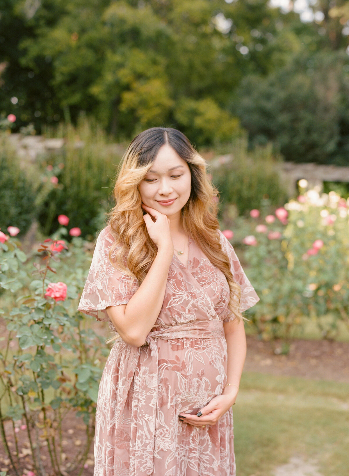 New mom poses for a portrait at the Raleigh Rose Garden. Image by Raleigh maternity photographer A.J. Dunlap Photography.