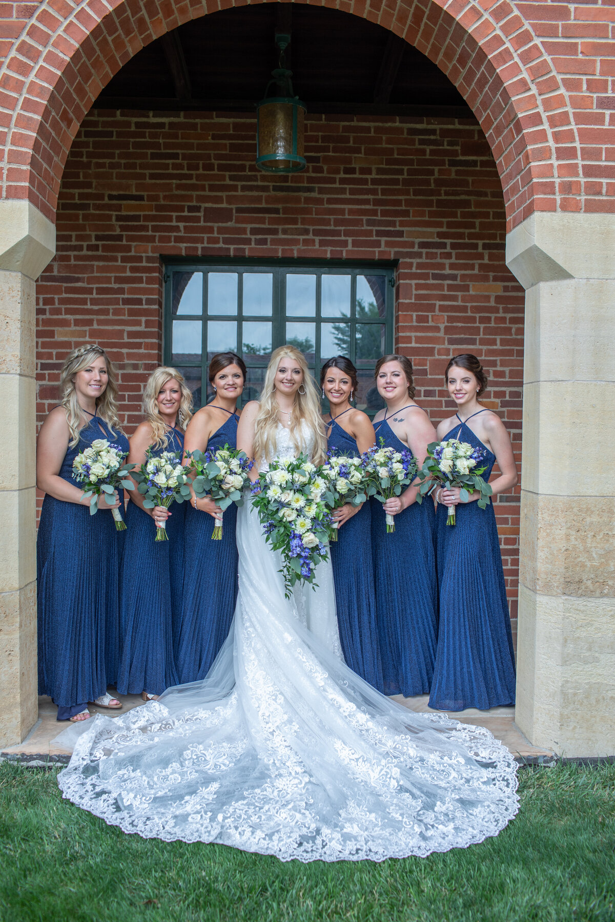Bride and her bridesmaids pose under an archway