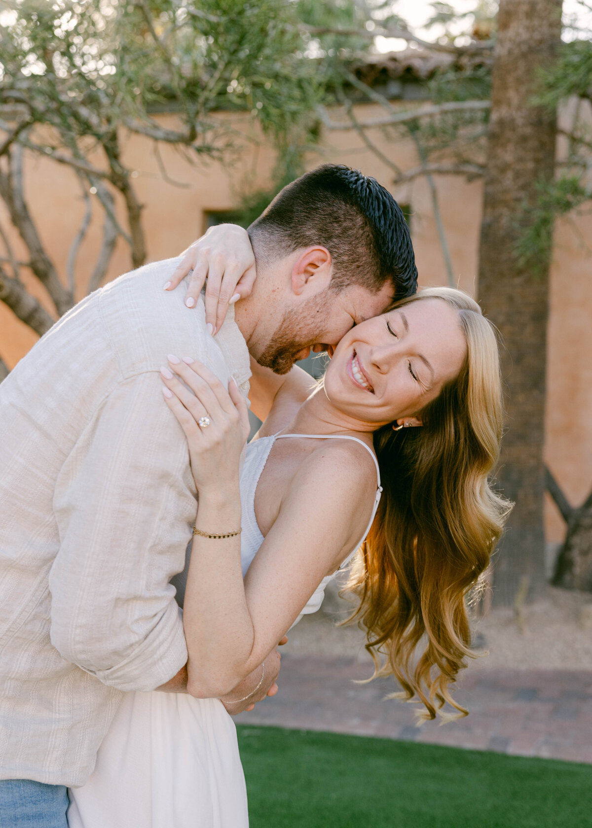 Couple hugging near lush palm trees at Royal Palms Resort engagement session
