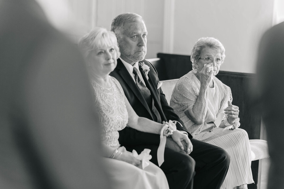 Candid wedding ceremony moment at Perkins Chapel in Dallas with the grandmother wiping away a tear and the parents looking emotional.