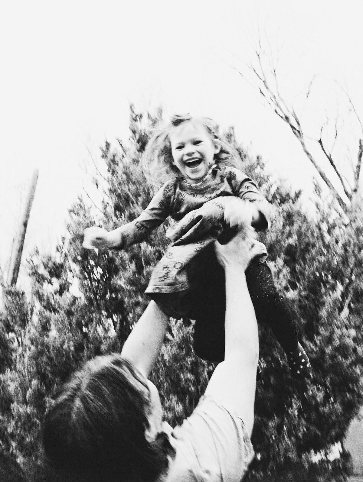 black and white photo of a dad throwing daughter in air