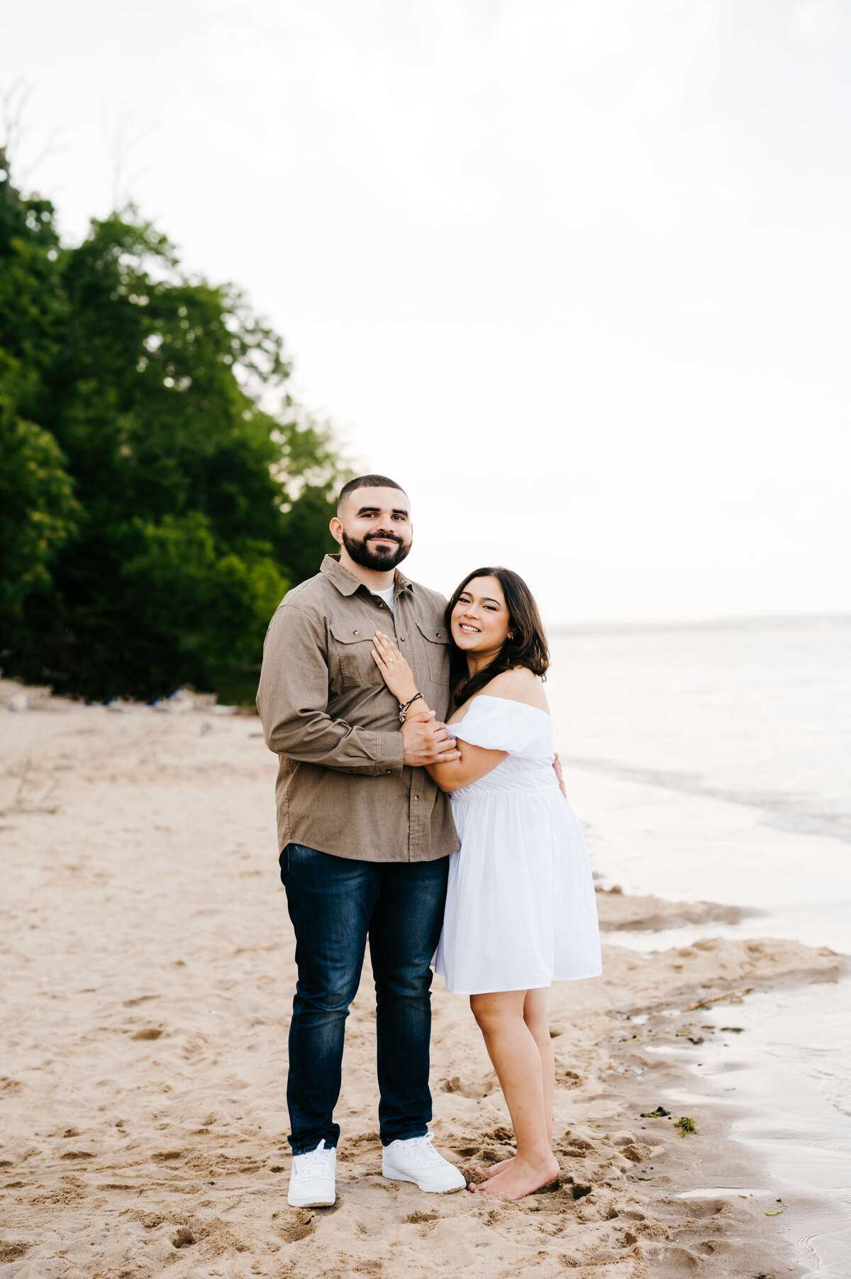 couples photography with man and woman posing together on the beach for their engagement