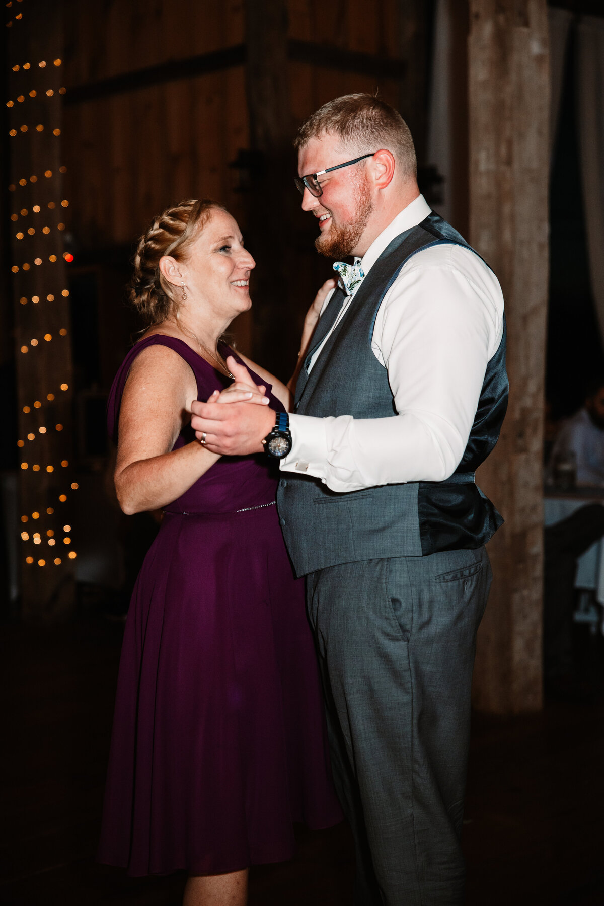 A woman in a purple dress dances with the groom without his jacket