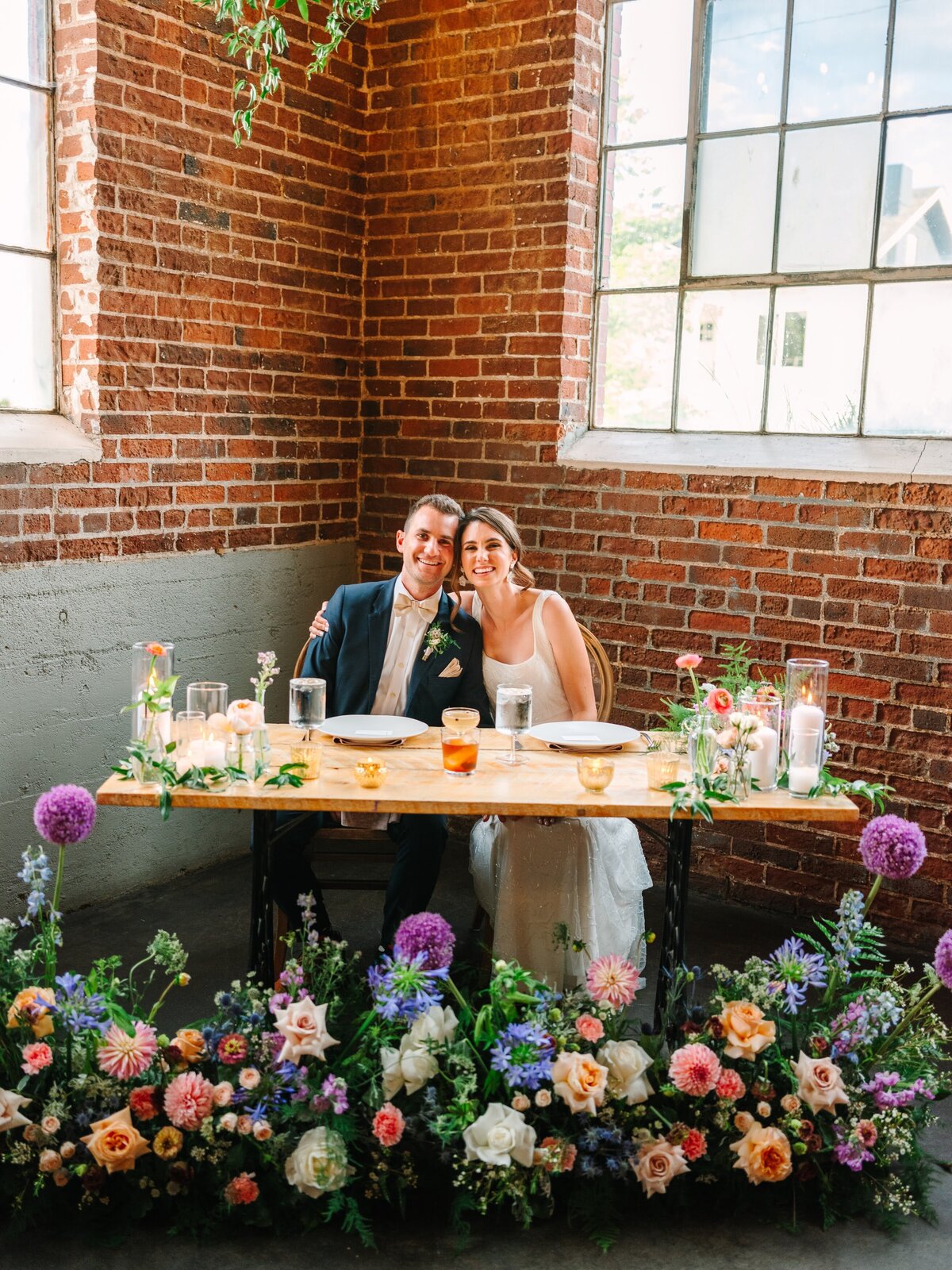 Bride and groom at their sweetheart table with Spring multi colored flowers.