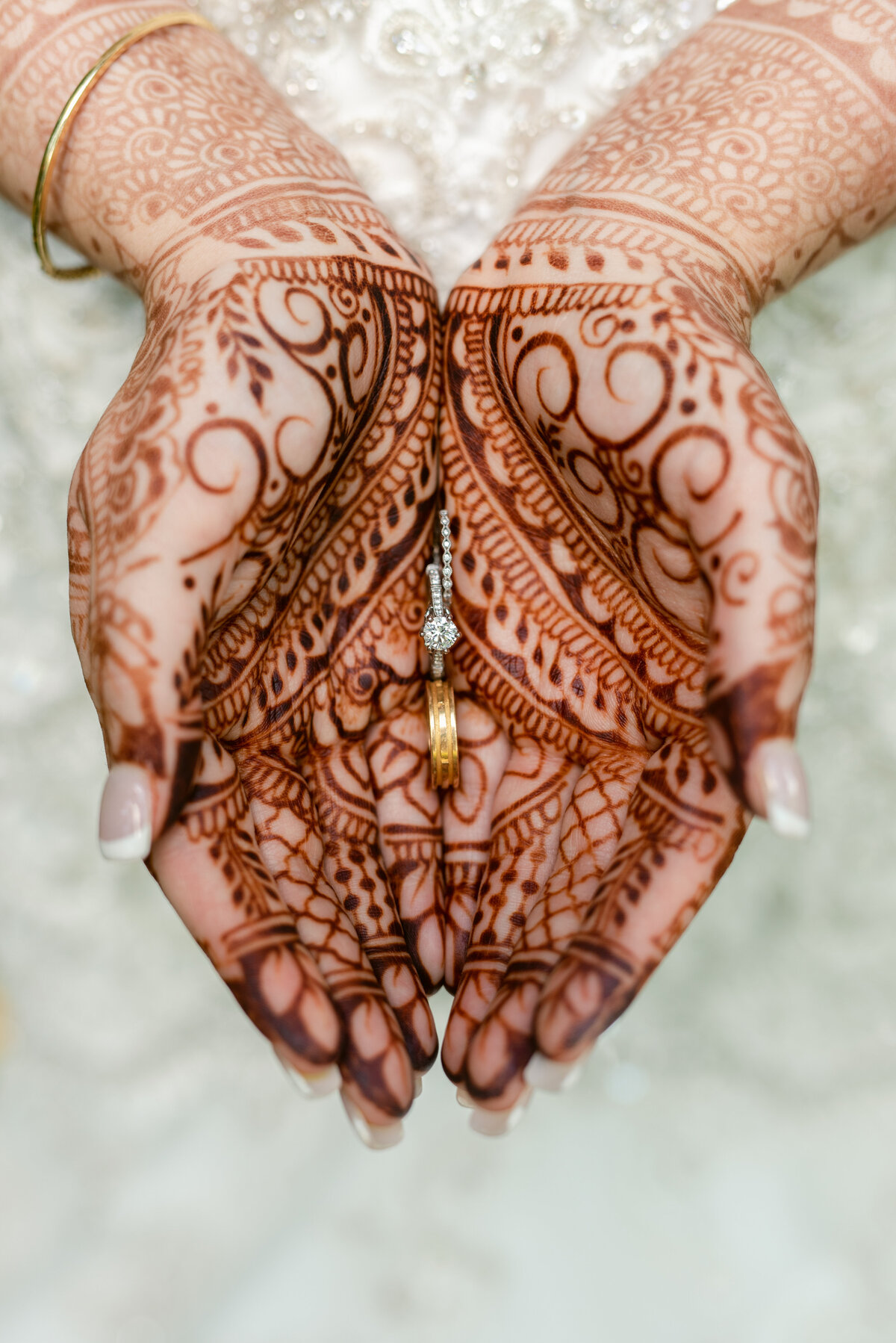 Bride holding wedding rings after henna ceremony.