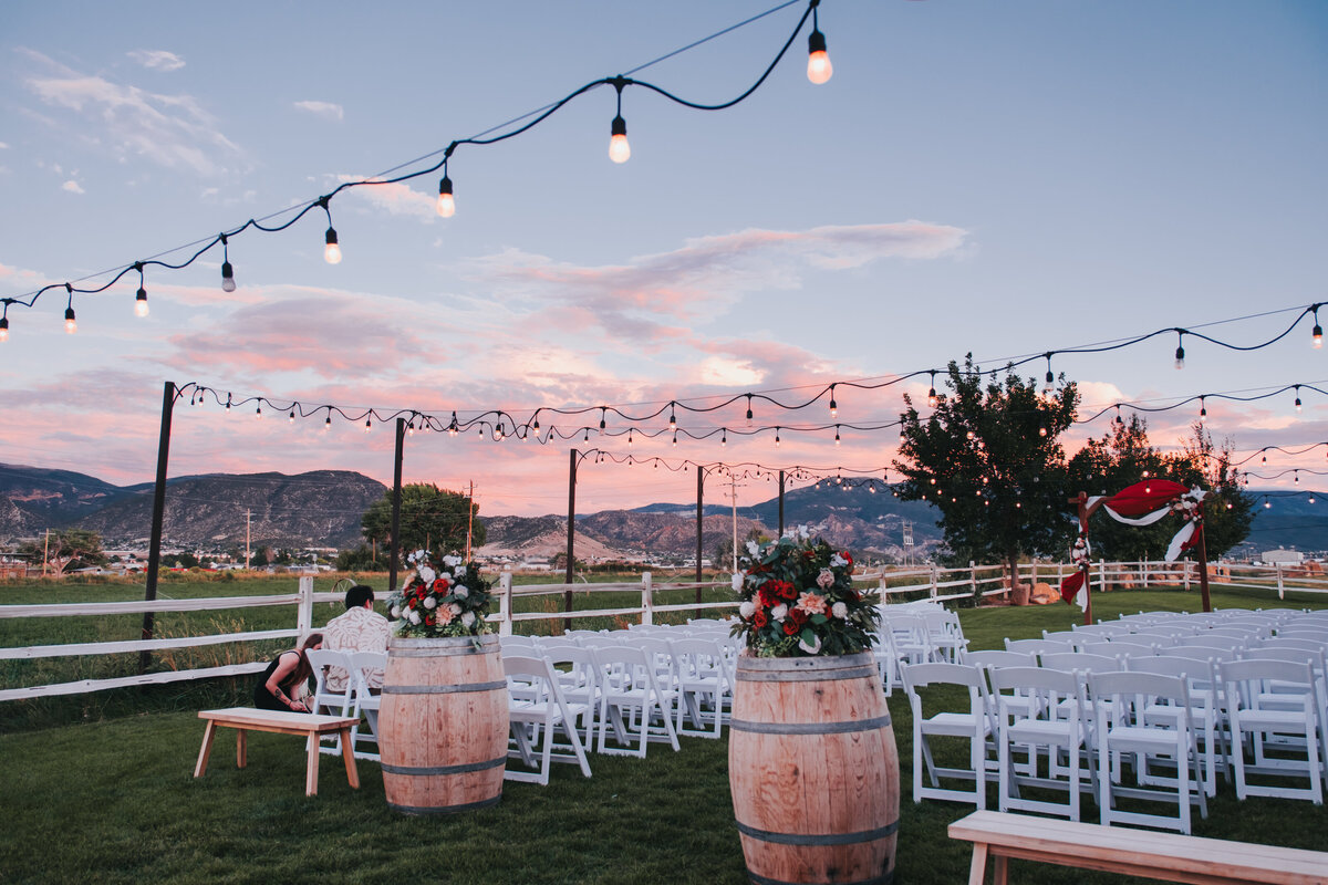 Outdoor ceremony seating with wine barrels under market lights at dusk