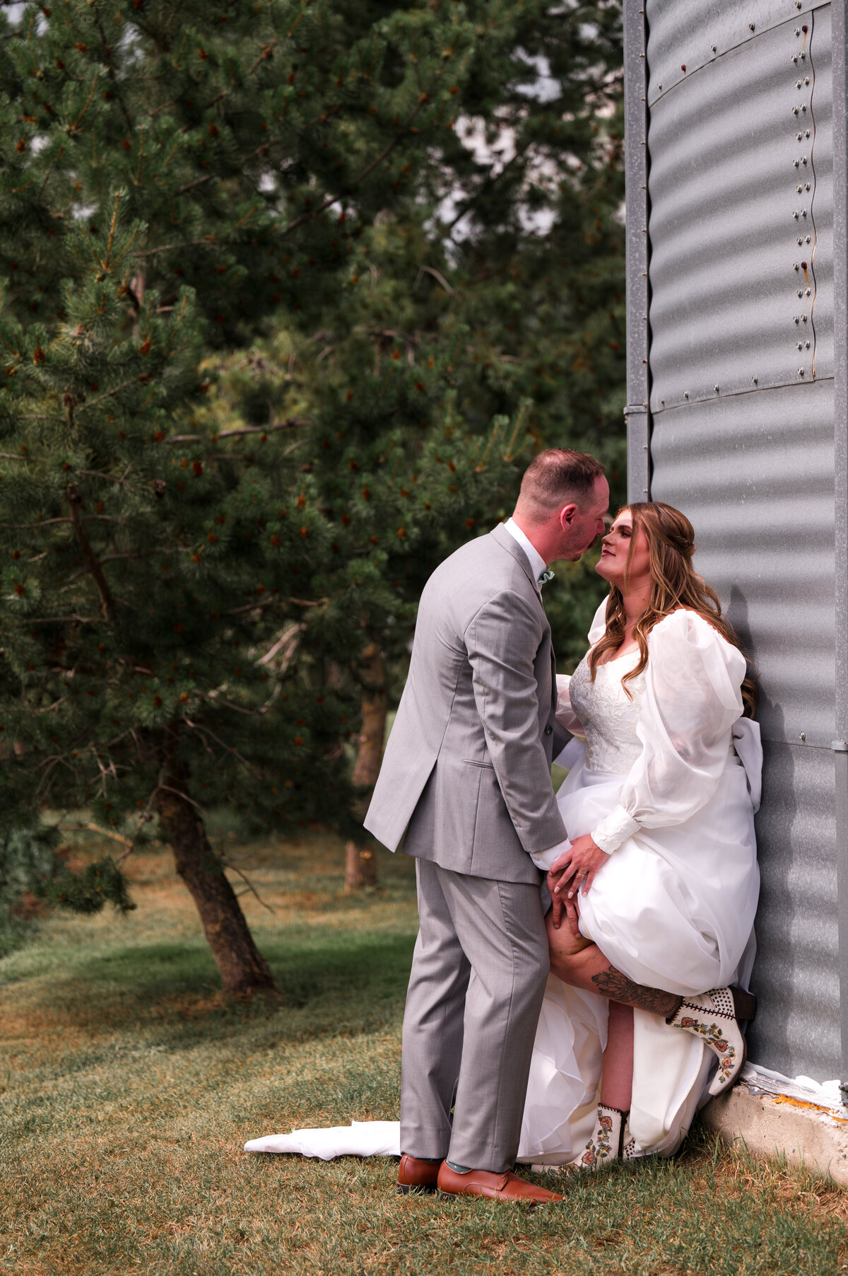 bride rests against a grain barrel during wedding photos