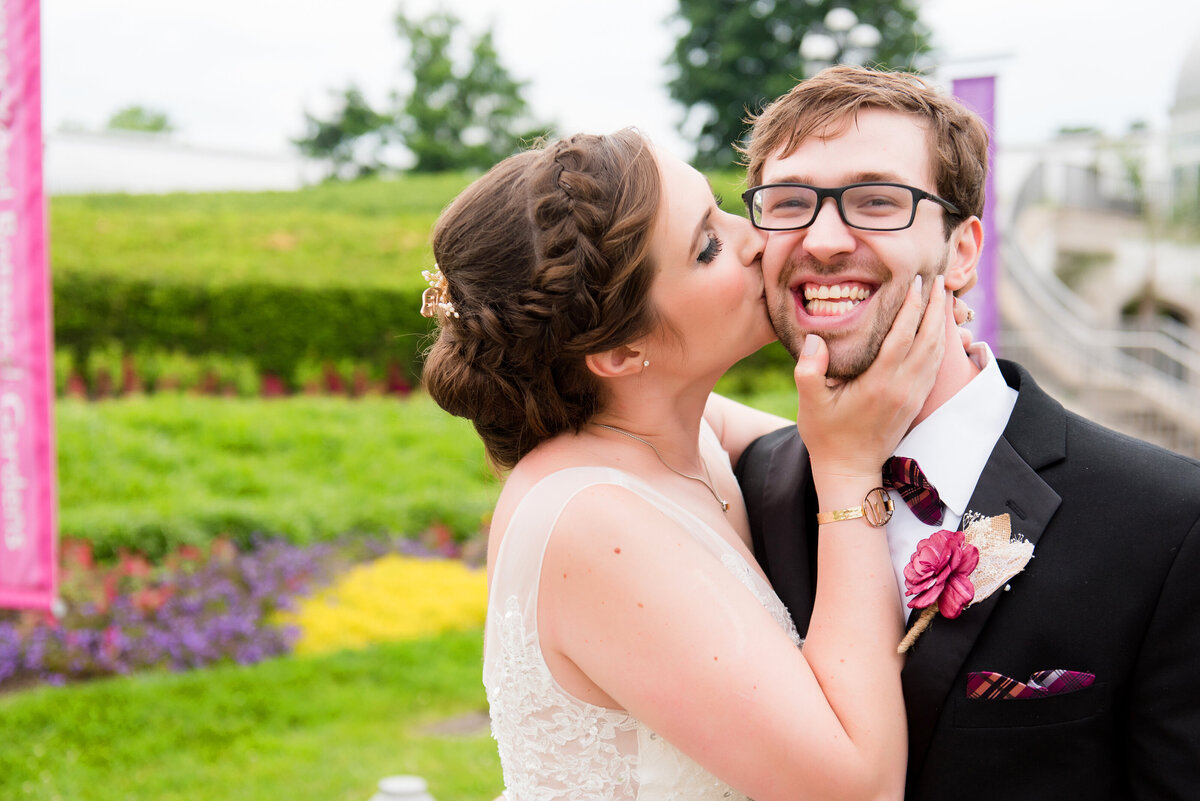 bride kissing groom on cheek with big smiles
