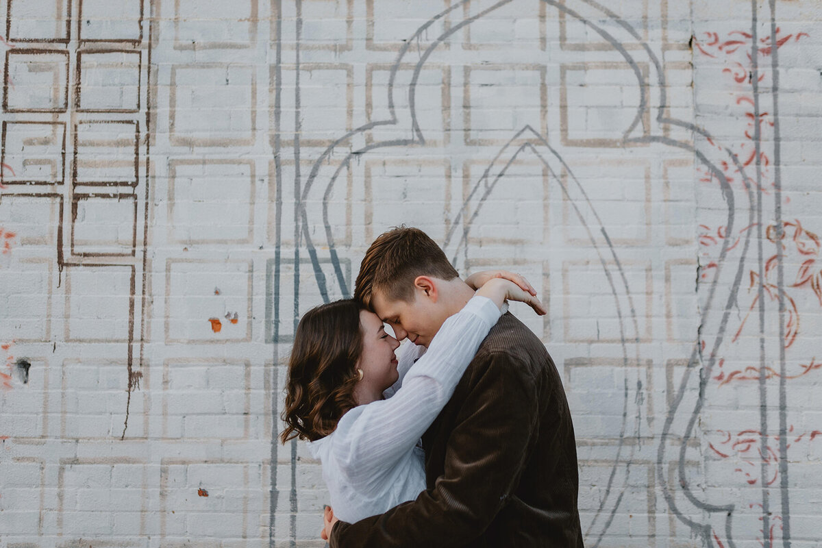 couple embrace in front of wall