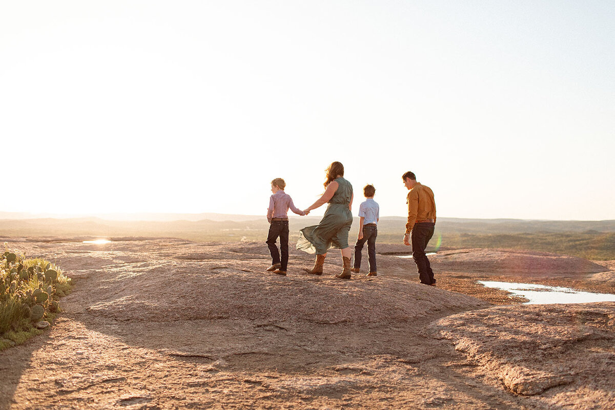 Silhouette of a family walking together outdoors, captured by Sara James, a San Antonio family photographer.