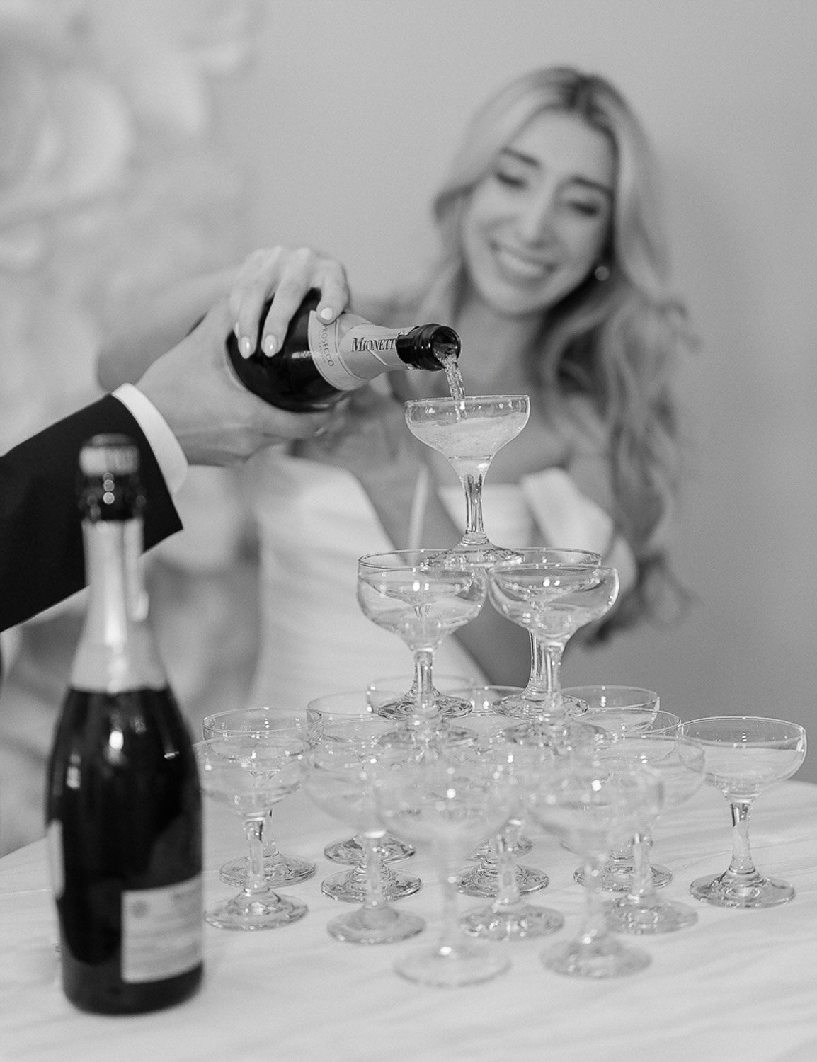 Les mariés versent du champagne dans une tour de verres de champagne pendant leur cocktail au mariage.