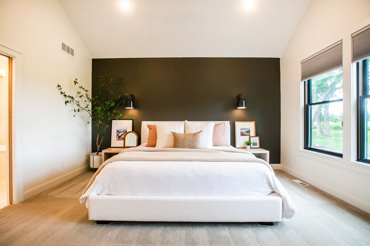 Spacious primary bedroom in custom Otsego home with natural light, wood floors and raised ceiling
