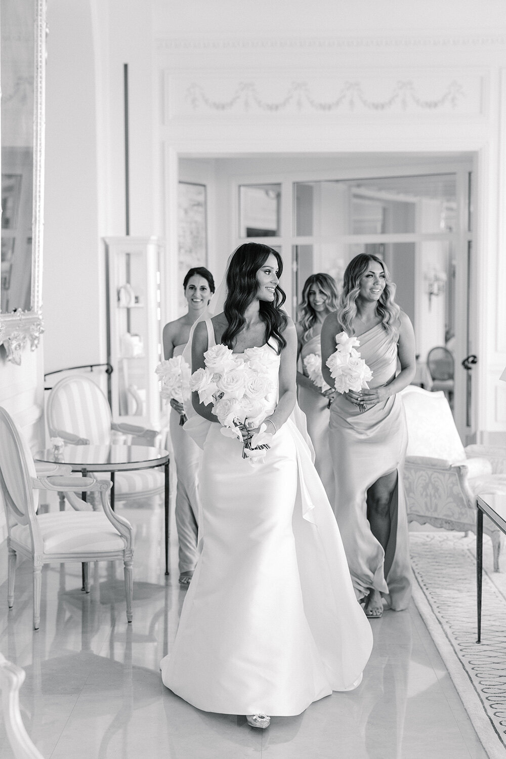 bride and bridesmaids walking through grand hotel du cap ferrat with all white rose bouquets