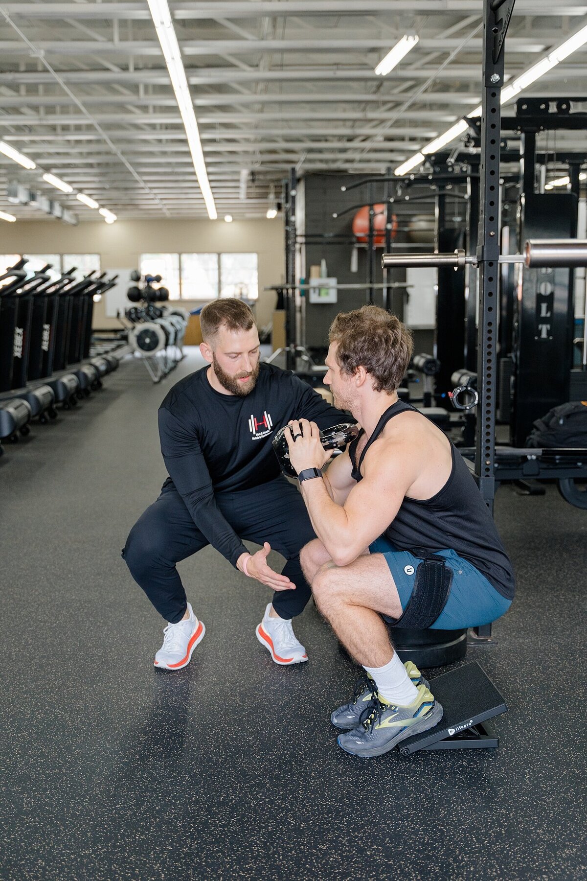 Columbus photographer captures personal training brand photos with trainer helping a man in a squat