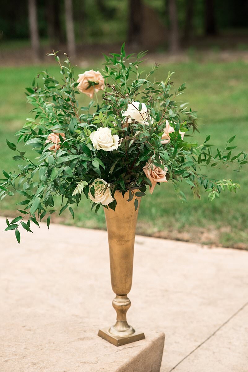 Gold trumpet arrangement with lush greenery, blush, and white roses