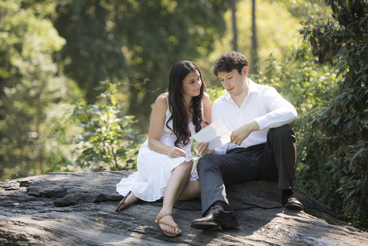 A couple sitting on a rock together reading a letter 