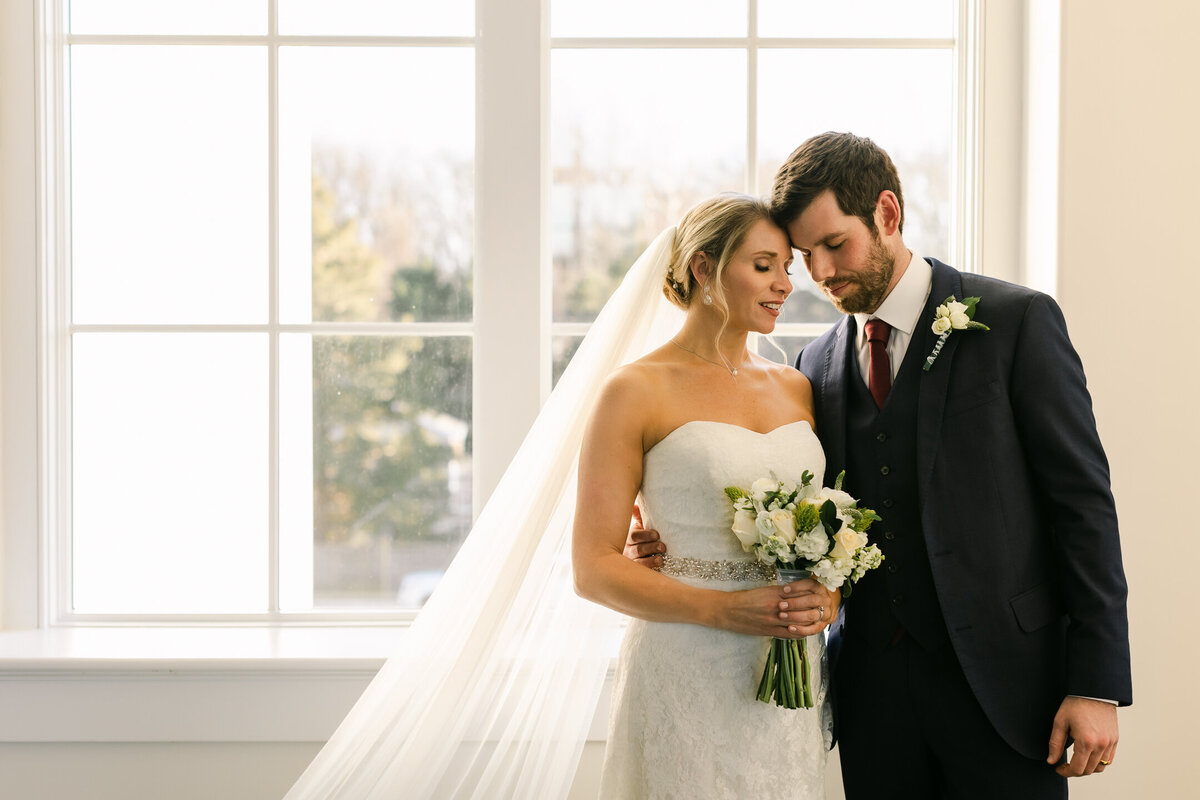 Wedding Photographer, a bride and groom stand together happy, she holds her bouquet