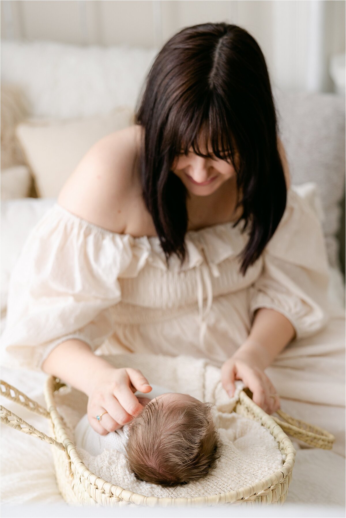 mother looking at baby in moses basket during indianapolis newborn photography session