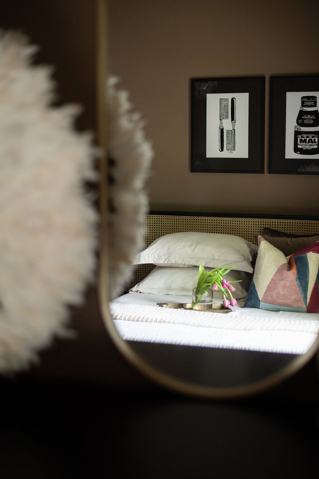 the reflection in a mirror showing a bed with artwork hanging above it