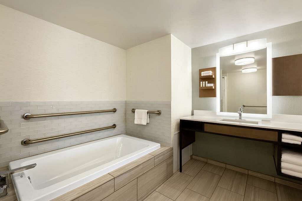 Modern hotel guest bathroom with LED mirror and ADA bathtub