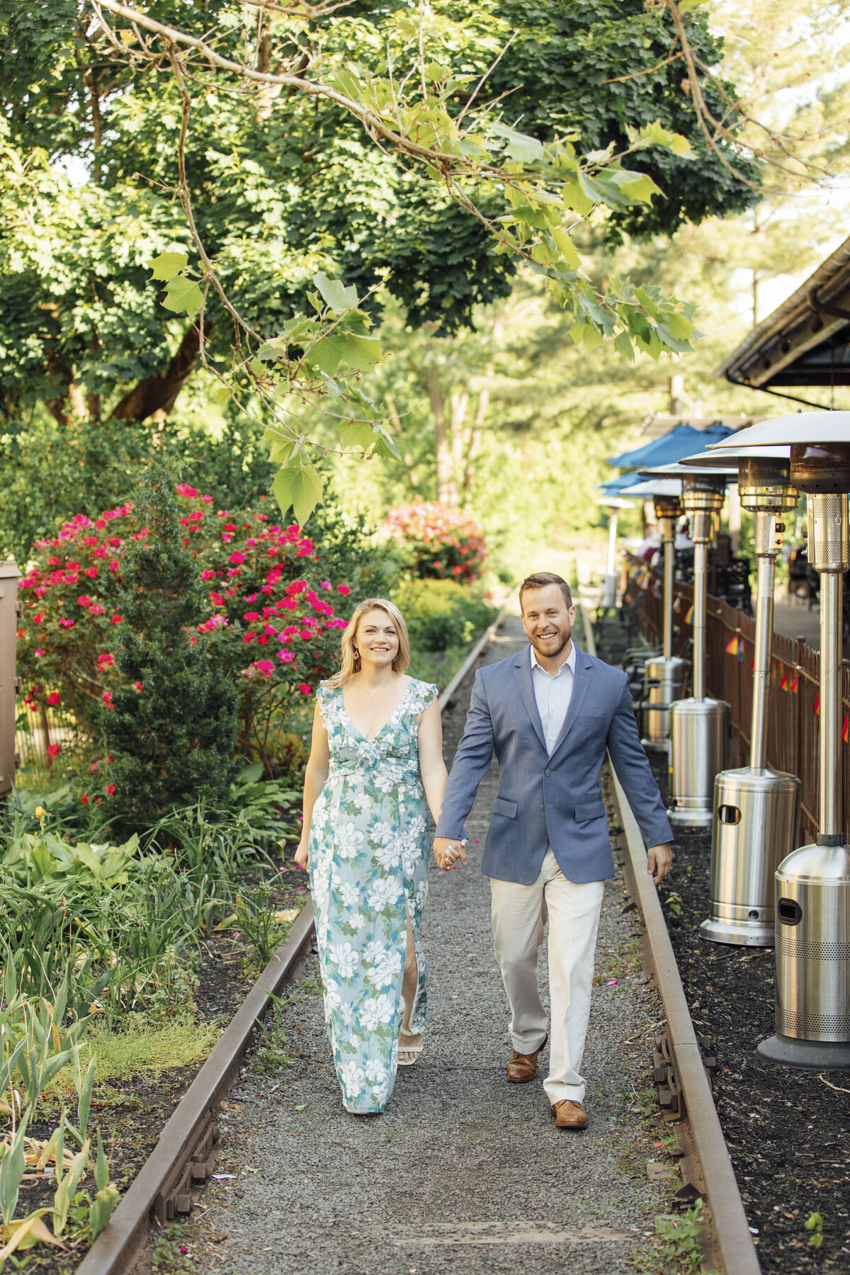 Romantic couple on train tracks with red roses during engagement session at Lambertville Station Inn in Hunterdon County New Jersey
