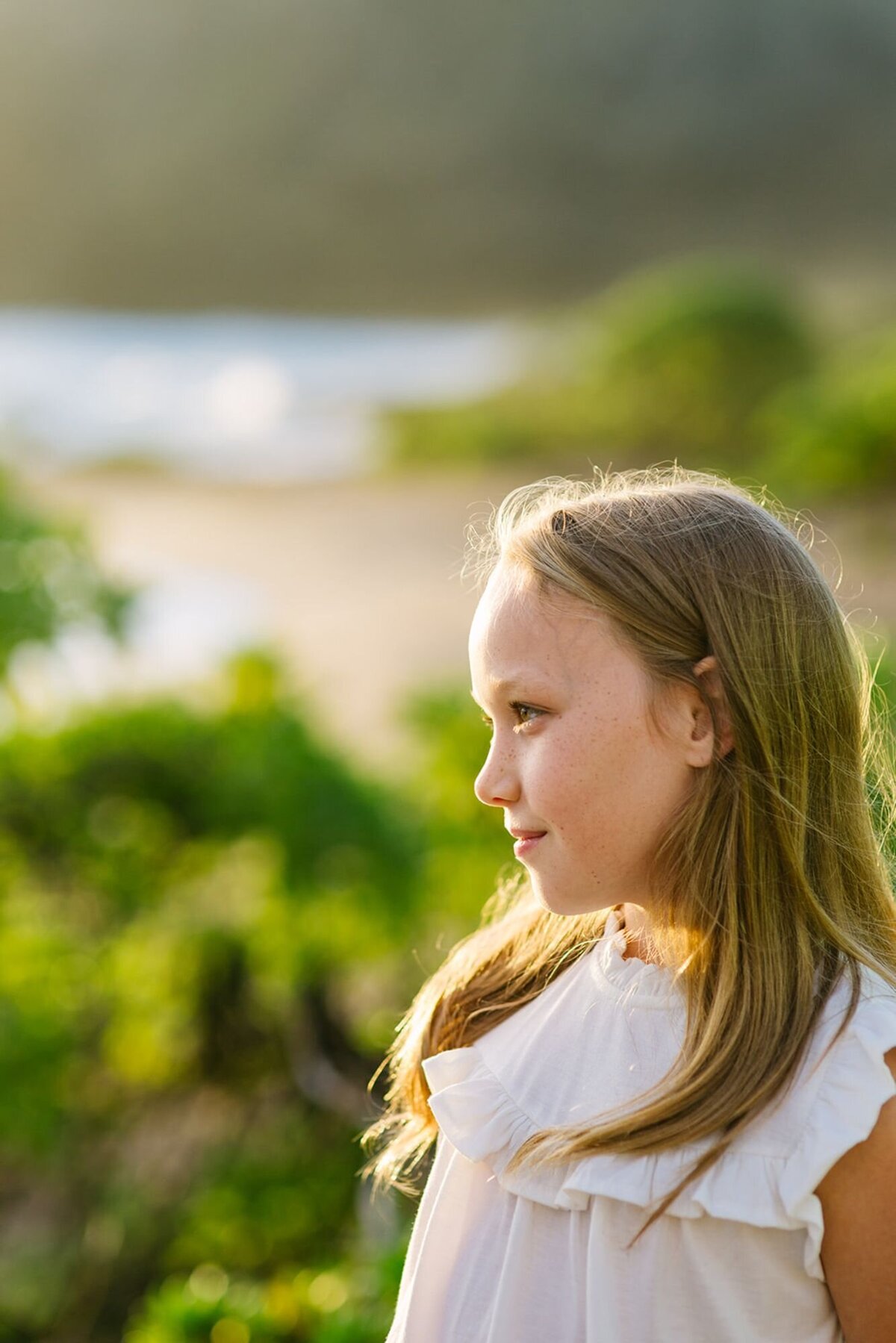 A young girl looks out in the distance on a beach.
