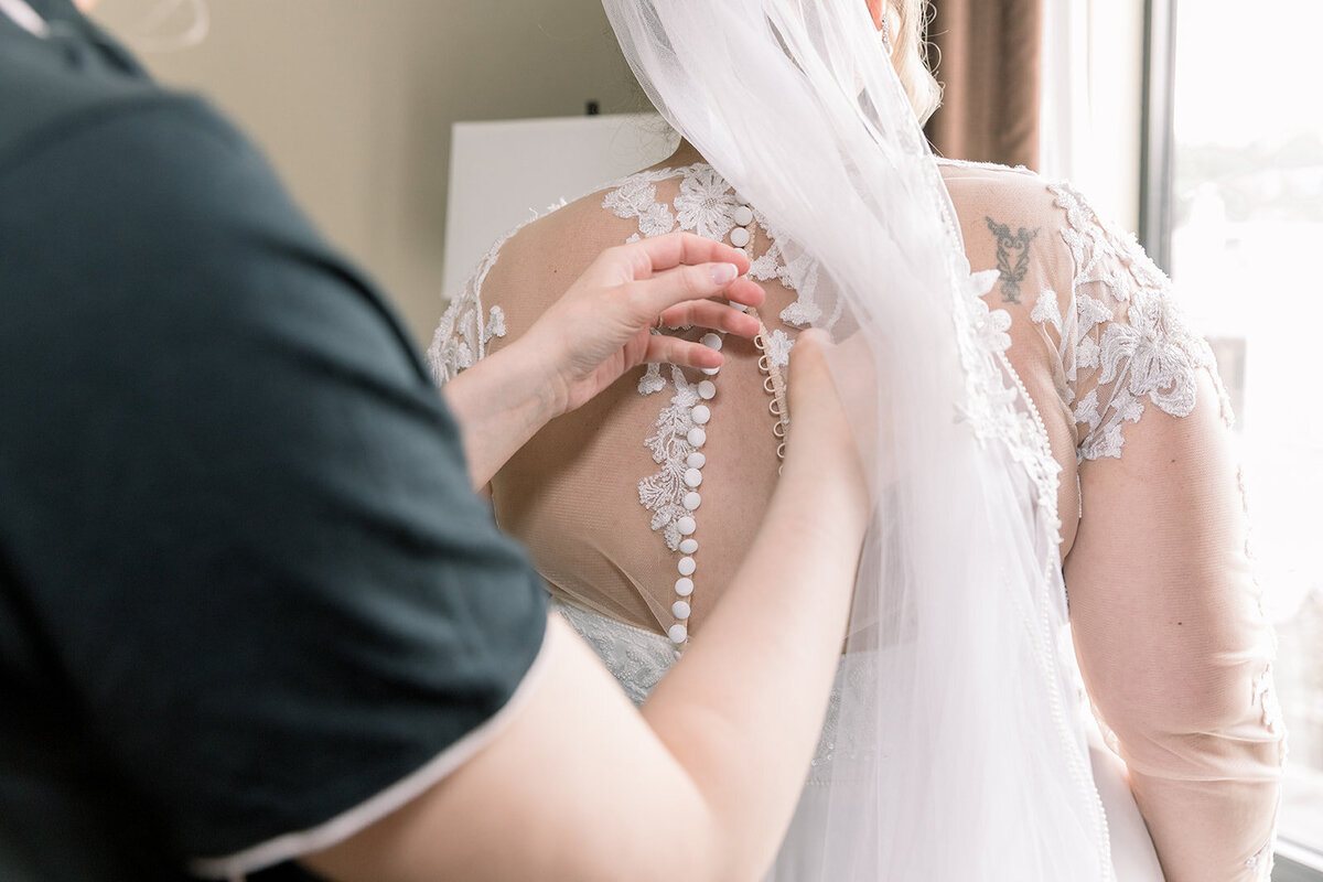 Back of a wedding dress with someone buttoning it up