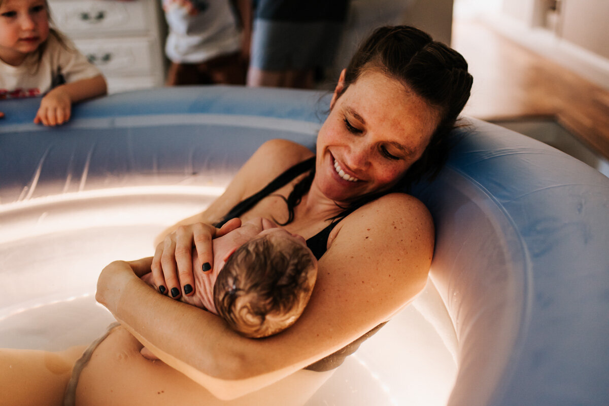 A serene image of a mother resting after labor, with her newborn cradled in her arms, capturing the peaceful aftermath of birth.