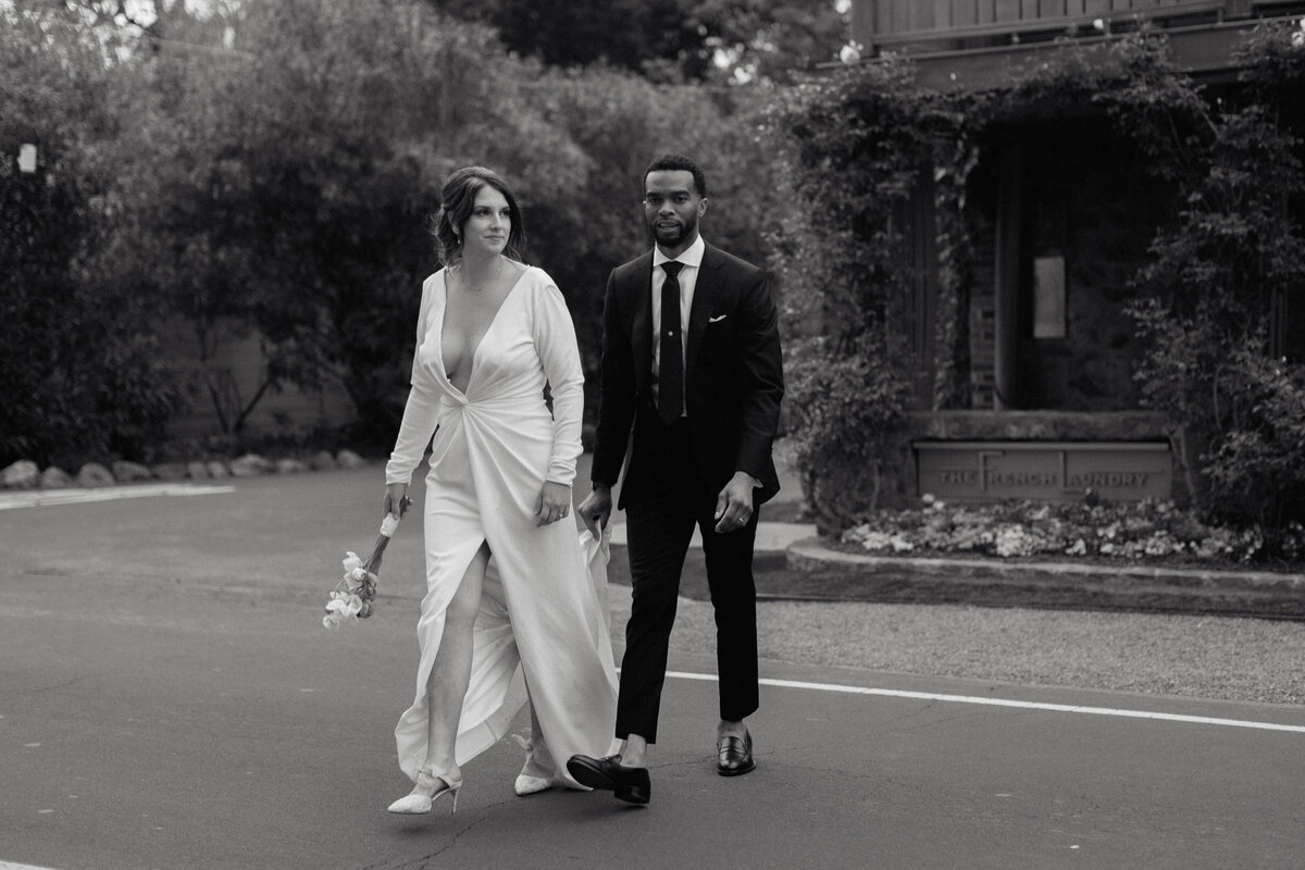 A candid black and white wedding portrait of a bride and groom walking together, exuding timeless elegance. We capture authentic love stories with a fine art documentary approach, specializing in natural, luxury wedding photography.