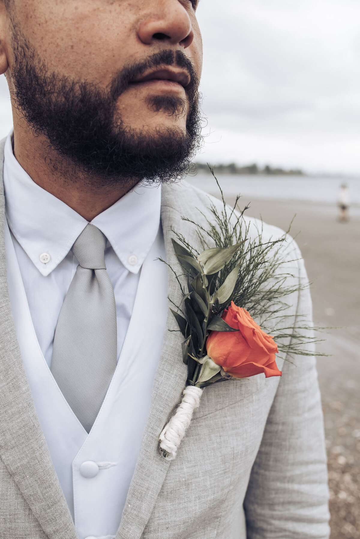 groom wearing a light gray suit with an orange rose boutonniere