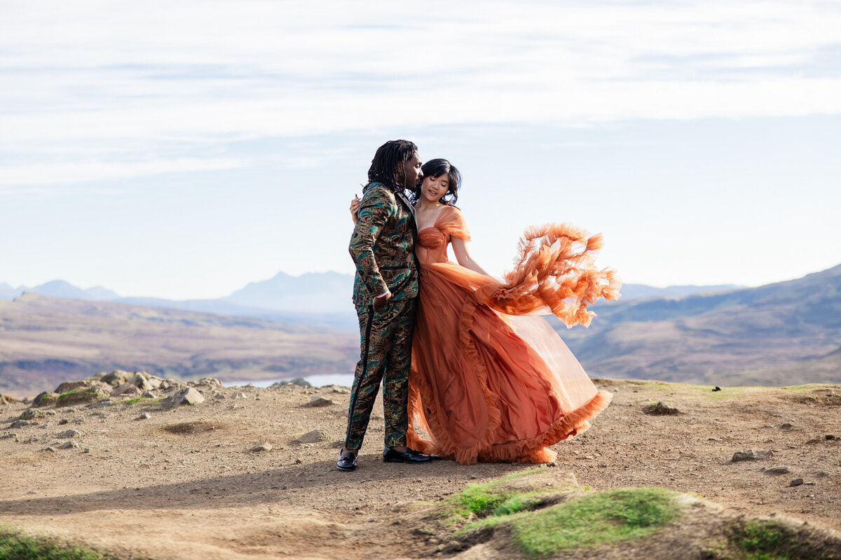bride tosses orange dress on a mountain top